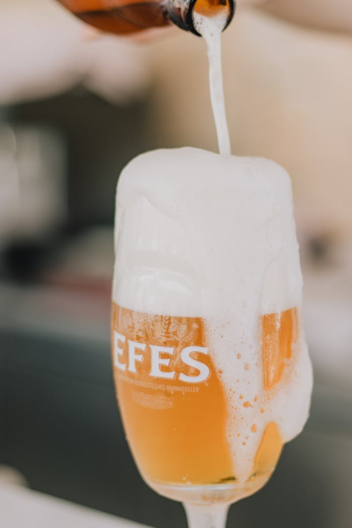 Close-up of beer being poured into a glass with foam overflowing, creating a refreshing visual.